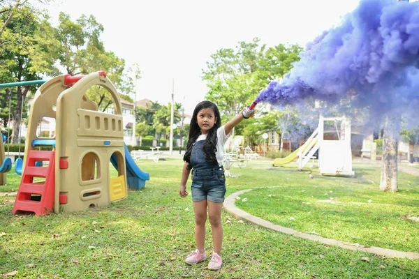 儿童游戏的概念 那个女孩正在花园里打烟雾 女孩愉快地微笑在公园里 — 图库照片