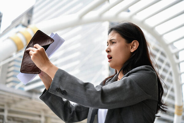 Concept of unemployed. Young business woman is stressed because of no money. Young businesswoman looking at the bill of credit.