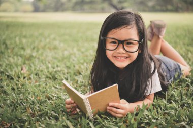 Eğitim kavramları. Kız bahçede bir kitap okuyor. Güzel kız gerçekten okuyor. Güzel kız mutlu öğrenme vardır.