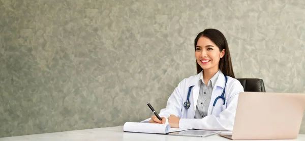 Smiling doctor posing in the office, She is wearing a stethoscope, medical staff on the hospital background