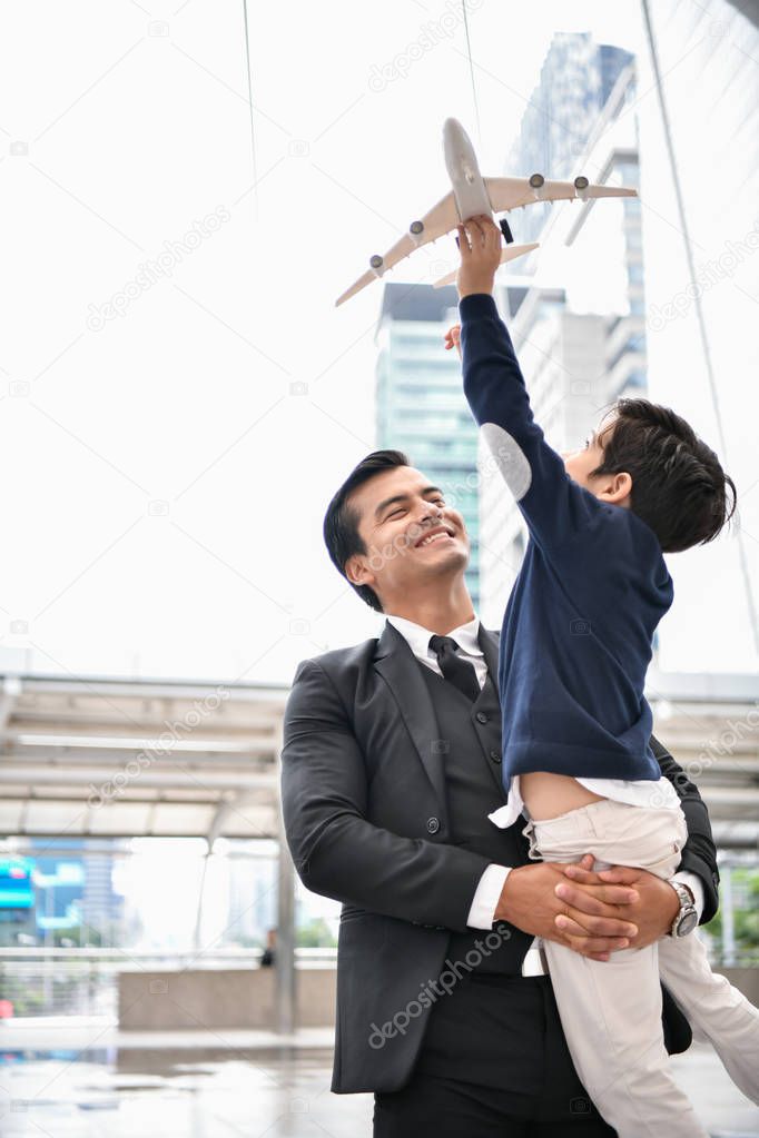 Family concept. Dad and son are playing fun toys. A businessman is carrying his son inside the city.