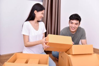 Konsept ev taşıma. Asya genç adam eşyalarını taşıyor. Genç Asyalı kadınlar eşyalarını bir kağıt kutu içinde tutuyor. Genç yeni evinde mutlu.