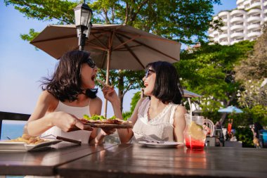 Boş zaman kavramı. Güzel kız seaside restoranda yemek yiyor. Güzel kız masaya yiyecek keyif alıyor.