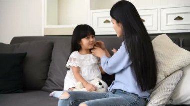 Aile konsepti. Anne oturma odasında kızı için giyiniyor..
