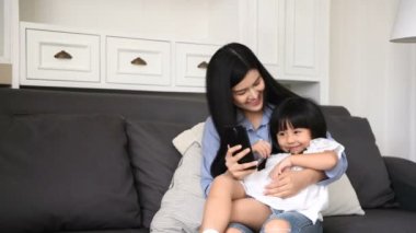 Aile konsepti. Anne kızını oturma odasında fotoğraf çekmeye davet ediyor..