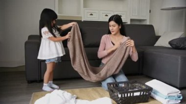 Aile konsepti. Anne ve kızı sepete kıyafet katlıyorlar..