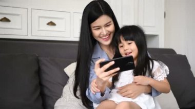 Aile Kavramı. Anne ve kızı evde cep telefonu oynuyor.