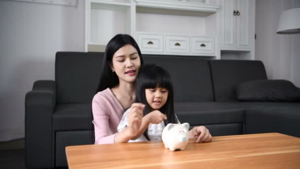 財務概念 母親は娘に貯金箱を落とす方法を教えている — ストック動画