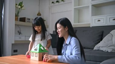 Aile konsepti. Anne ve kızı oturma odasında birlikte aktiviteler yapıyorlar..