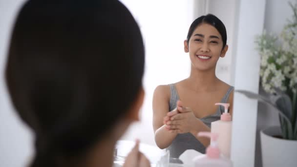 美容コンセプト 女性は鏡にスキンクリームを塗っている — ストック動画