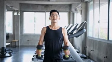 Egzersiz konsepti. Genç adam spor salonunda dambılı kaldırıyor..