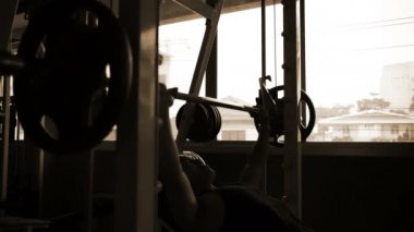 Egzersiz konsepti. Genç adamın gölgesi spor salonunda ağırlığı kaldırıyor..