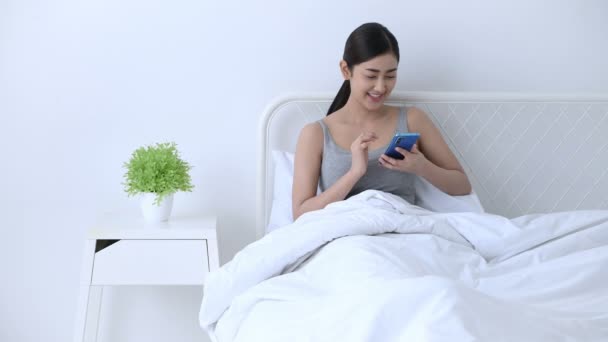 Concepto de vacaciones. Asiáticas chicas están jugando teléfonos móviles en el dormitorio . — Vídeo de stock