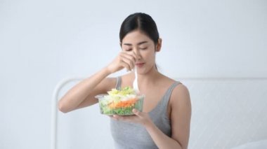 Sağlık kavramı. Asyalı kızlar yatak odasında sebze salatası yiyor.