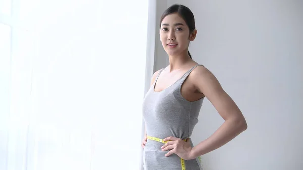 Gesundes Konzept. asiatische Mädchen sind messen Ihr Taille in die Zimmer — Stockfoto