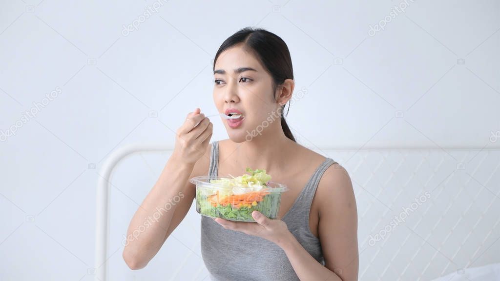 Health concept. Asian girls are eating vegetables salad in the b