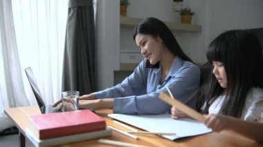 Tatil konsepti. Annem evde çalışıyor ve kızına bakıyor. 4k Çözünürlüğü.