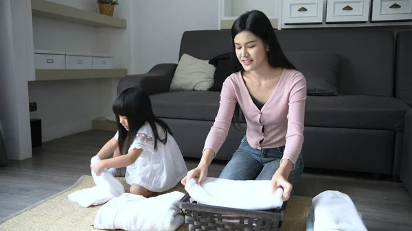 Concepto de vacaciones. La hija está ayudando a su madre a doblar la ropa en la canasta. Resolución 4k . — Foto de Stock