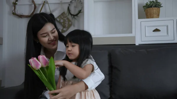 Concepto de vacaciones. La hija trae flores para sorprenderle. — Foto de Stock