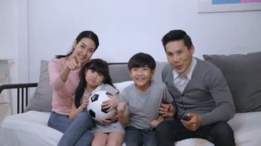 Aile kavramı. Ebeveynler ve çocuklar evde birlikte futbol oynuyorlar. 4k Çözünürlüğü.