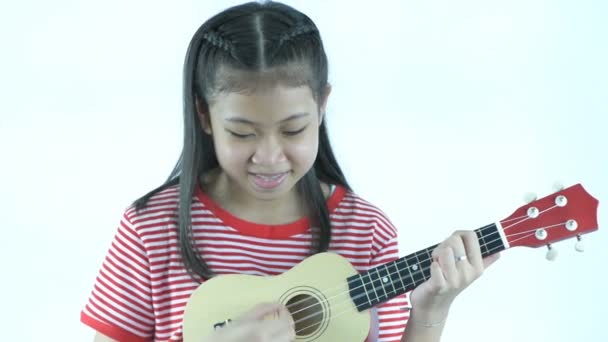 白い背景で楽しいウクレレを演奏する若い女の子 4K分解能 — ストック動画
