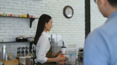 İş konsepti. Barista müşterilerine gülümseyerek kahve veriyor. 4k Çözünürlüğü.