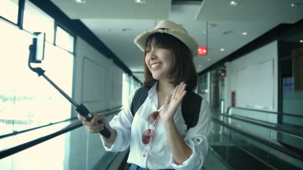 観光コンセプト アジアの女性が空港内でビデオ通話をしています 4K分解能 — ストック動画