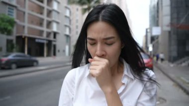 Seyahat konsepti. Trafik geçmişinde öksüren Asyalı kadın. 4k Çözünürlüğü.