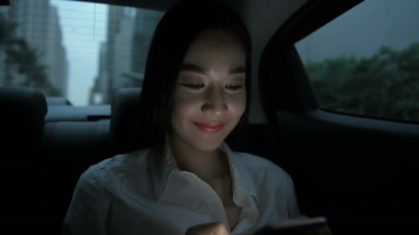 旅行のコンセプト タクシーに乗っている間にアジアの女性が携帯電話で遊んでいる 4K分解能 — ストック動画