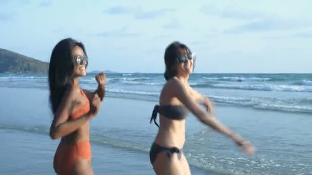 假期的概念 两个穿着比基尼的漂亮姑娘在海滩上跳舞 4K分辨率 — 图库视频影像