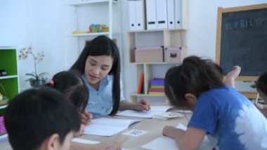 (Çince çeviri: Adınız nedir?) Öğretmen çocuklara parlak bir gülen yüzle sınıfta Çince öğrenmeyi öğretiyor..