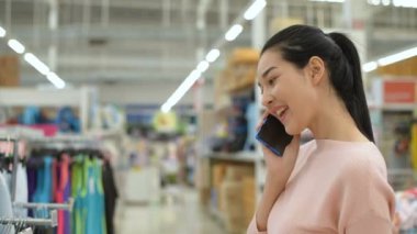 Alışveriş kavramları. Alışveriş merkezinde Asyalı bir kadın telefonda konuşuyor. 4k Çözünürlüğü.