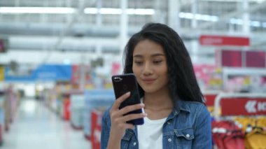 Alışveriş kavramları. Güzel kadınlar alışveriş merkezinde alışveriş yapmak için cep telefonu kullanıyorlar. 4k Çözünürlüğü.
