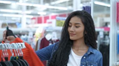 Alışveriş kavramları. Kız alışveriş merkezindeki kıyafetleri deniyor. 4k Çözünürlüğü.