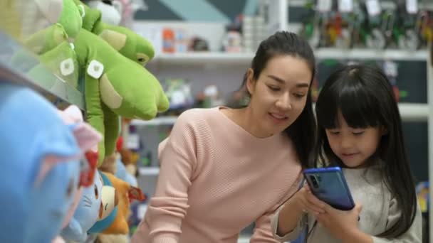 购物的概念 亚洲的母亲和女儿正在购物中心里买洋娃娃 4K分辨率 — 图库视频影像