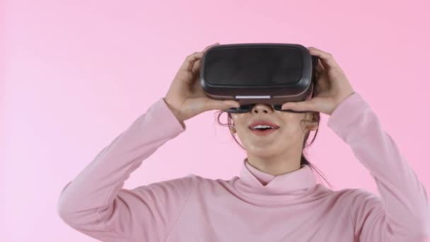 美丽的概念 穿着虚拟现实Vr眼镜头盔头戴粉色背景头盔的年轻女性微笑 4K分辨率 — 图库视频影像