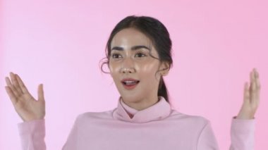 Güzellik konsepti. Güzel Asyalı kız pembe arka planda şaşkınlıkla gözlerini açıyor. 4k Çözünürlüğü.