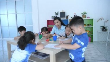 Eğitici kavramlar. Öğretmen sınıfta resim çizmeyi anaokulu çocuklarına öğretiyor. 4k Çözünürlüğü.