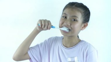 Sağlık kavramları. Beyaz arka planda dişlerini fırçalayan Asyalı bir kız. 4k Çözünürlüğü.