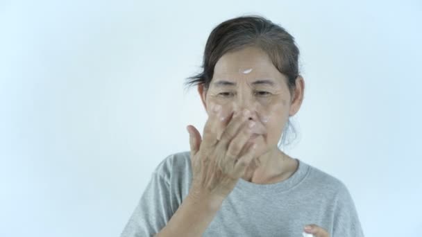 Schoonheidsconcept Een Oude Vrouw Die Crème Aanbrengt Een Witte Achtergrond — Stockvideo