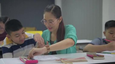 Eğitim konsepti. Öğretmen engelli çocuklara resim çizmeyi ve resim yapmayı öğretiyor. 4k Çözünürlüğü.