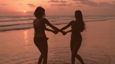 Seyahat konsepti. İki Asyalı kadın sahilde eğleniyor. 4k Çözünürlüğü.