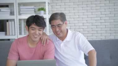 Aile kavramı. Baba ve oğul bilgisayar kullanarak iletişim kuruyor. 4k Çözünürlüğü.