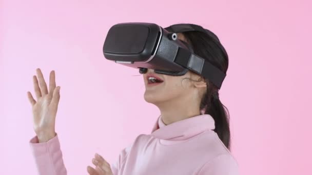 美丽的概念 穿着虚拟现实Vr眼镜头盔头戴粉色背景头盔的年轻女性微笑 4K分辨率 — 图库视频影像