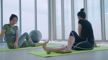 Egzersiz konsepti. Spor salonunda esneme hareketleri yapan bayan sporcular. 4k Çözünürlüğü.