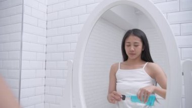 Günlük rutin konsept. Genç Asyalı kadın banyoda gargara yapıyor. 4k Çözünürlüğü.