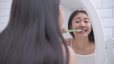 Günlük rutin konsept. Banyoda diş fırçalayan Asyalı kadın. 4k Çözünürlüğü.