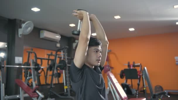 フィットネスコンセプト 若いアジア系男性はジムでダンベルを持ち上げる 4K分解能 — ストック動画