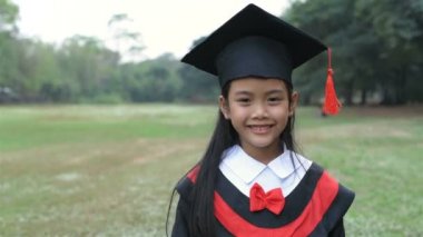 Eğitici kavramlar. Mezuniyet elbisesi giyen kız bahçede mutlu. 4k Çözünürlüğü.