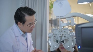 Optik dükkan konsepti. Göz doktoru, özel bir makineyle hastanın gözlerini inceliyor. - Ne? 4k Çözünürlüğü.